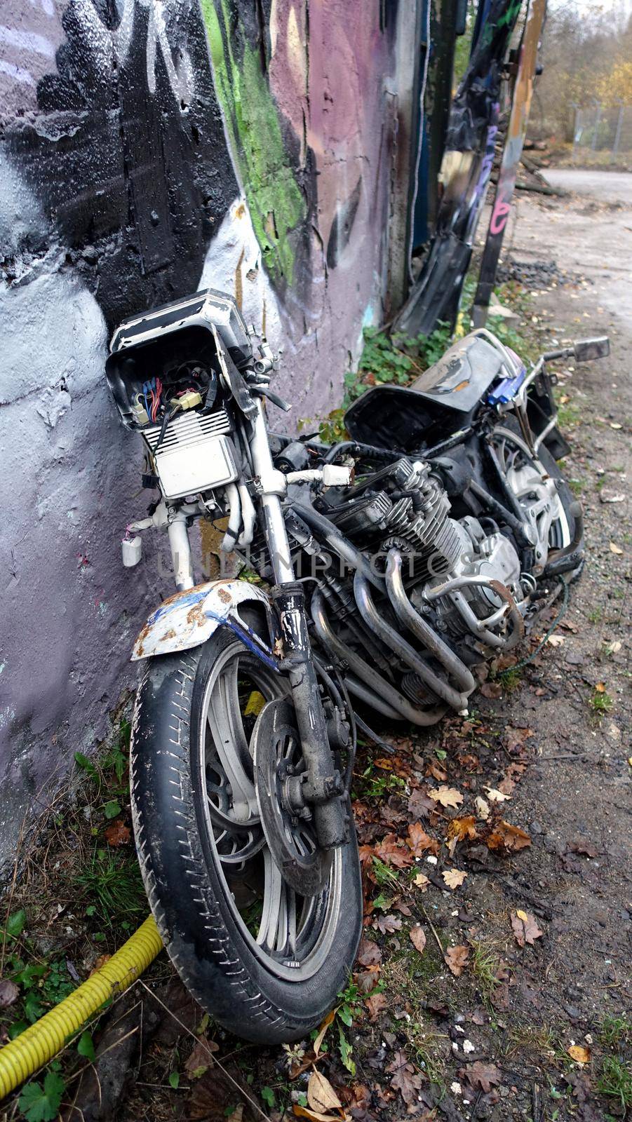 Stockholm, Snosatra, October 28, 2020. An old abandoned motorcycle leaning against a colorful wall