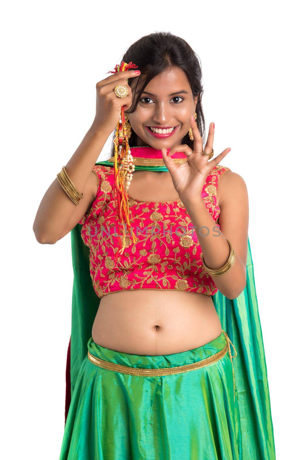 Beautiful girl showing Rakhi on occasion of Raksha bandhan on a white background. Sister tie Rakhi as symbol of intense love for her brother.