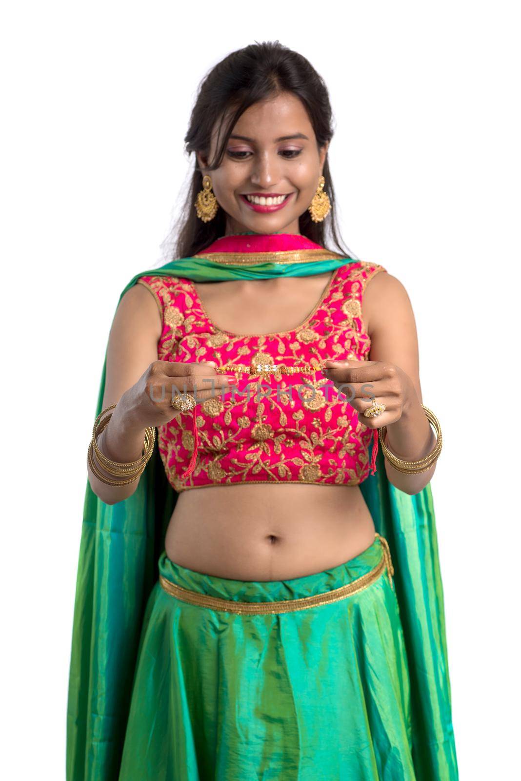 Beautiful girl showing Rakhi on occasion of Raksha bandhan on a white background. Sister tie Rakhi as symbol of intense love for her brother.