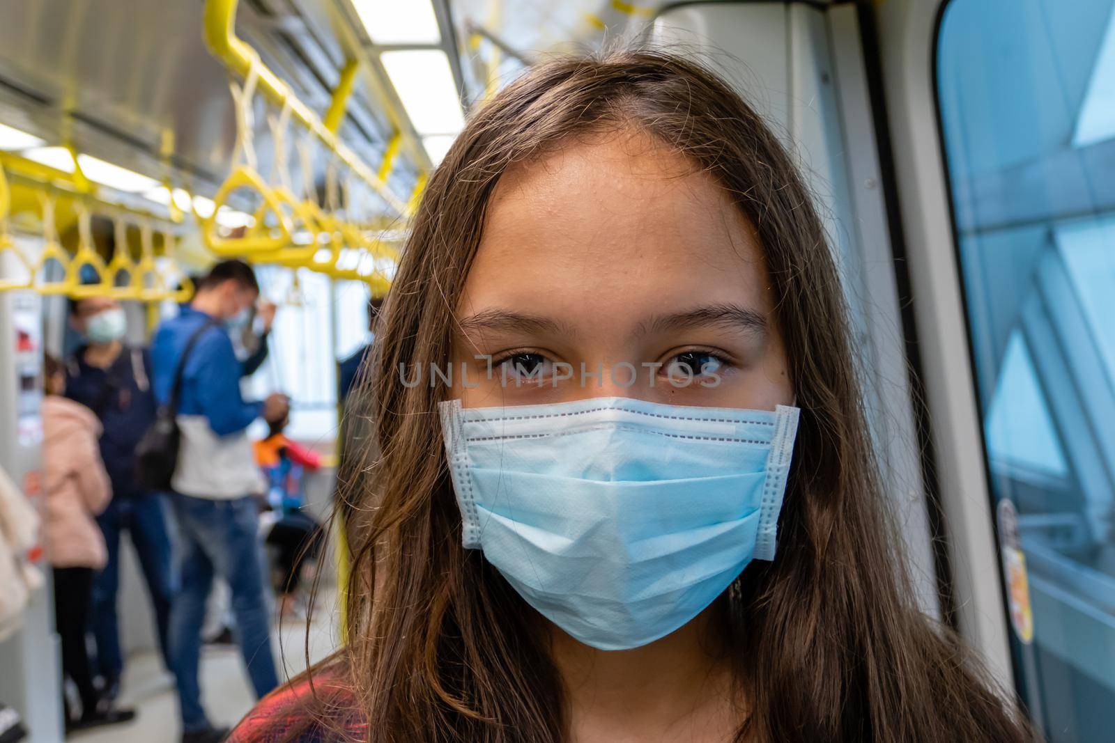 Young Asian American girl wearing surgical mask on subway