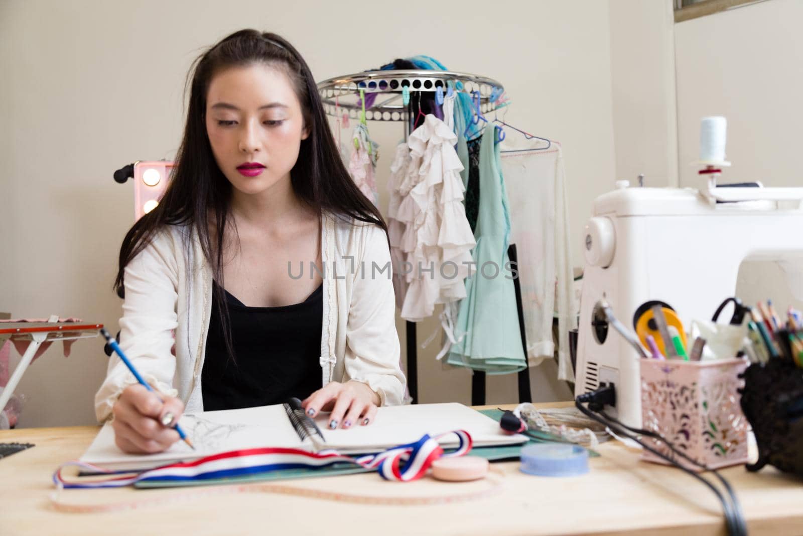 Young Asian American fashion designer sketching design