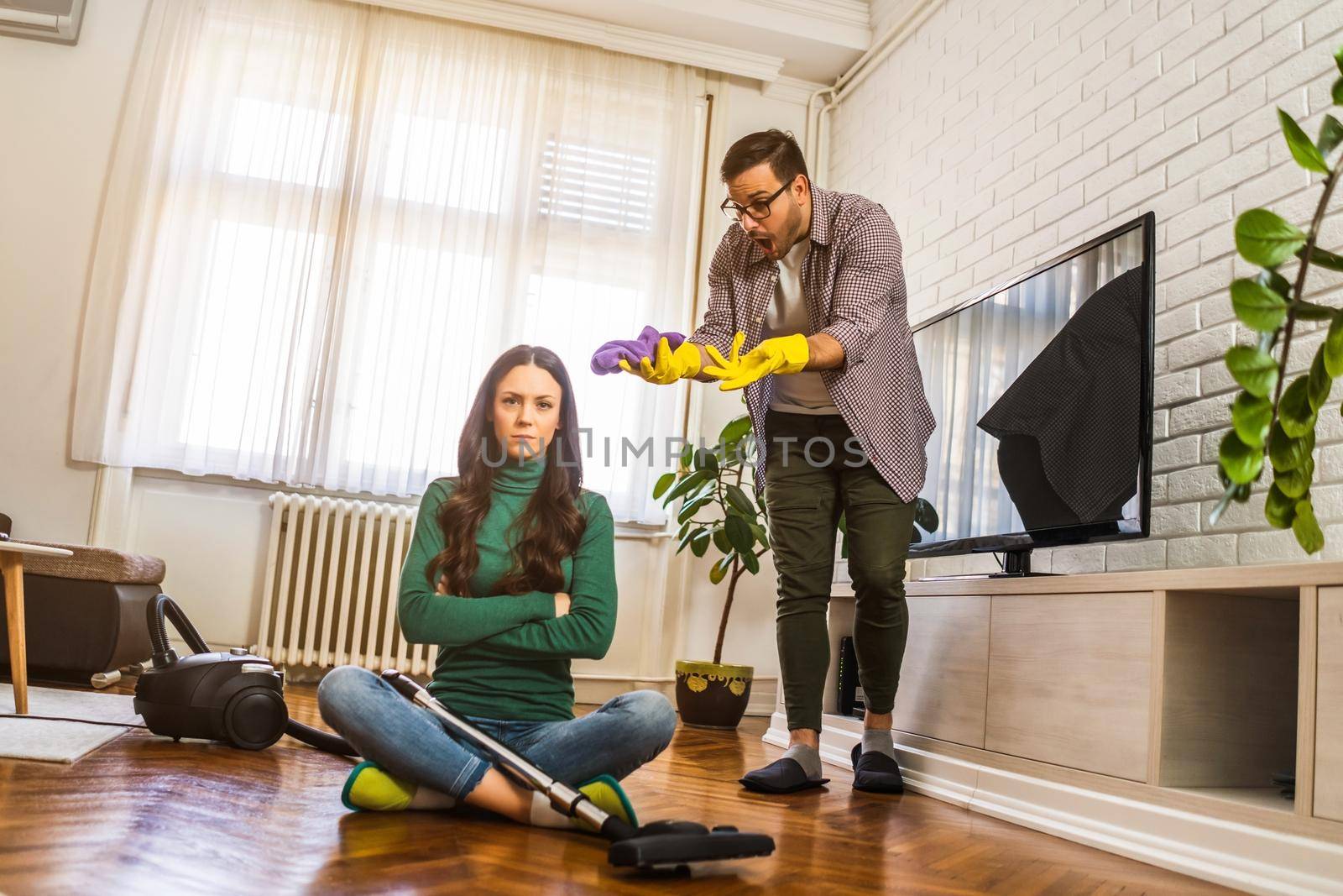 Woman is lazy. Man is telling her to continue cleaning their apartment.