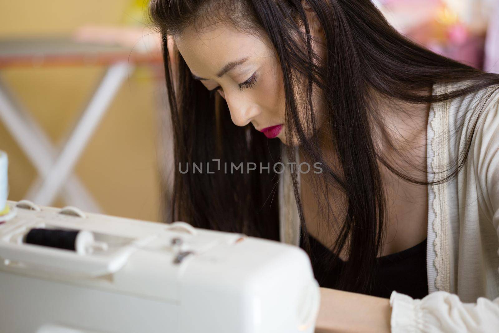 Young Asian American fashion designer at sewing machine