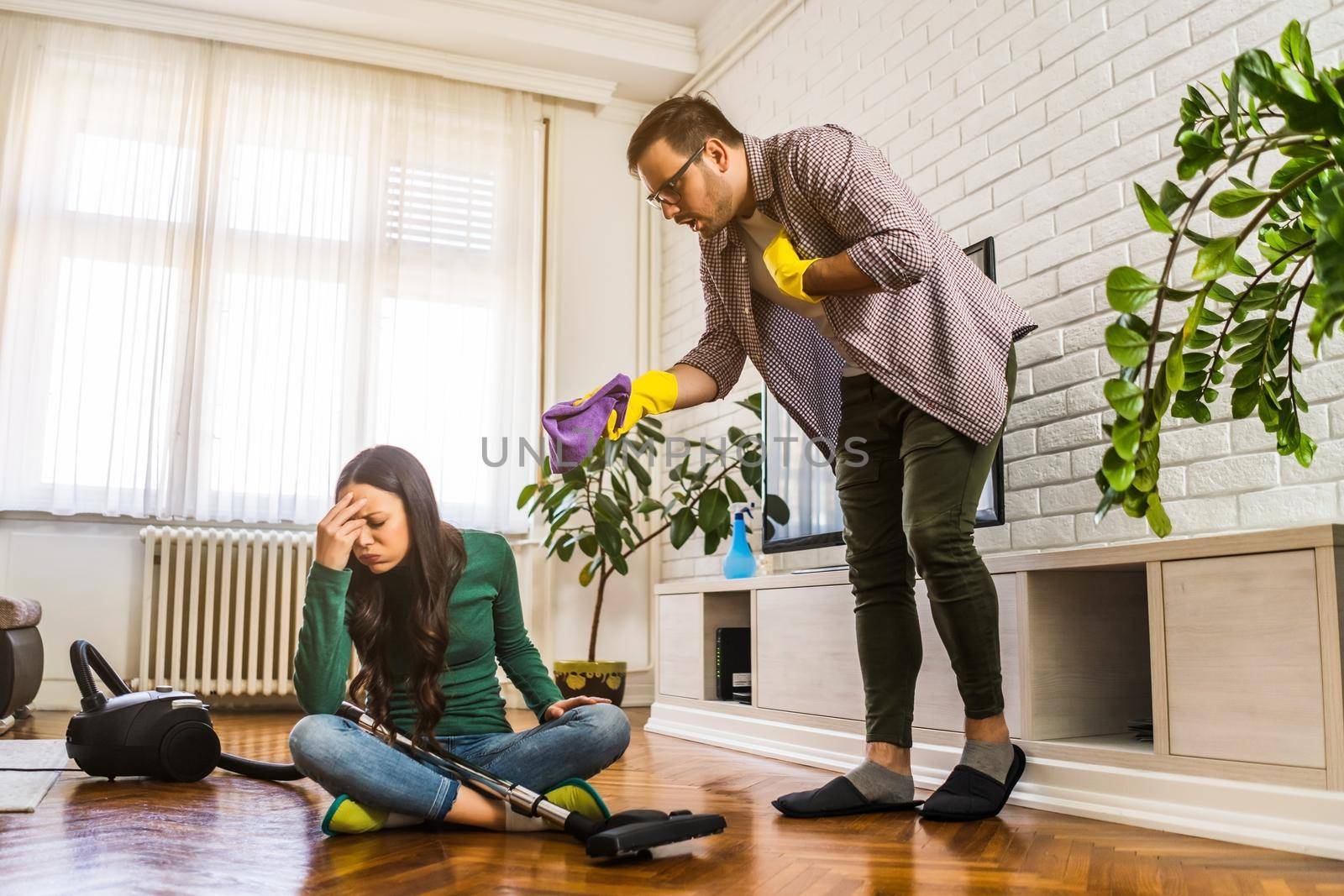 Woman is lazy. Man is telling her to continue cleaning their apartment.