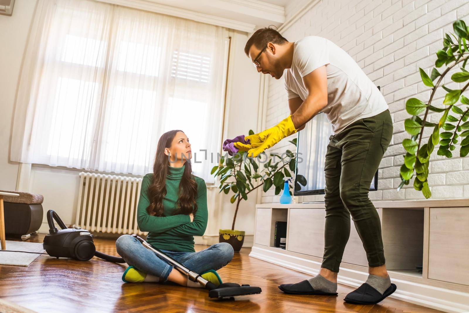 Woman is lazy. Man is telling her to continue cleaning their apartment.