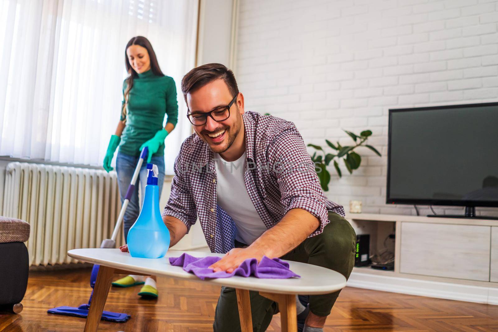 Young happy couple is cleaning their apartment.