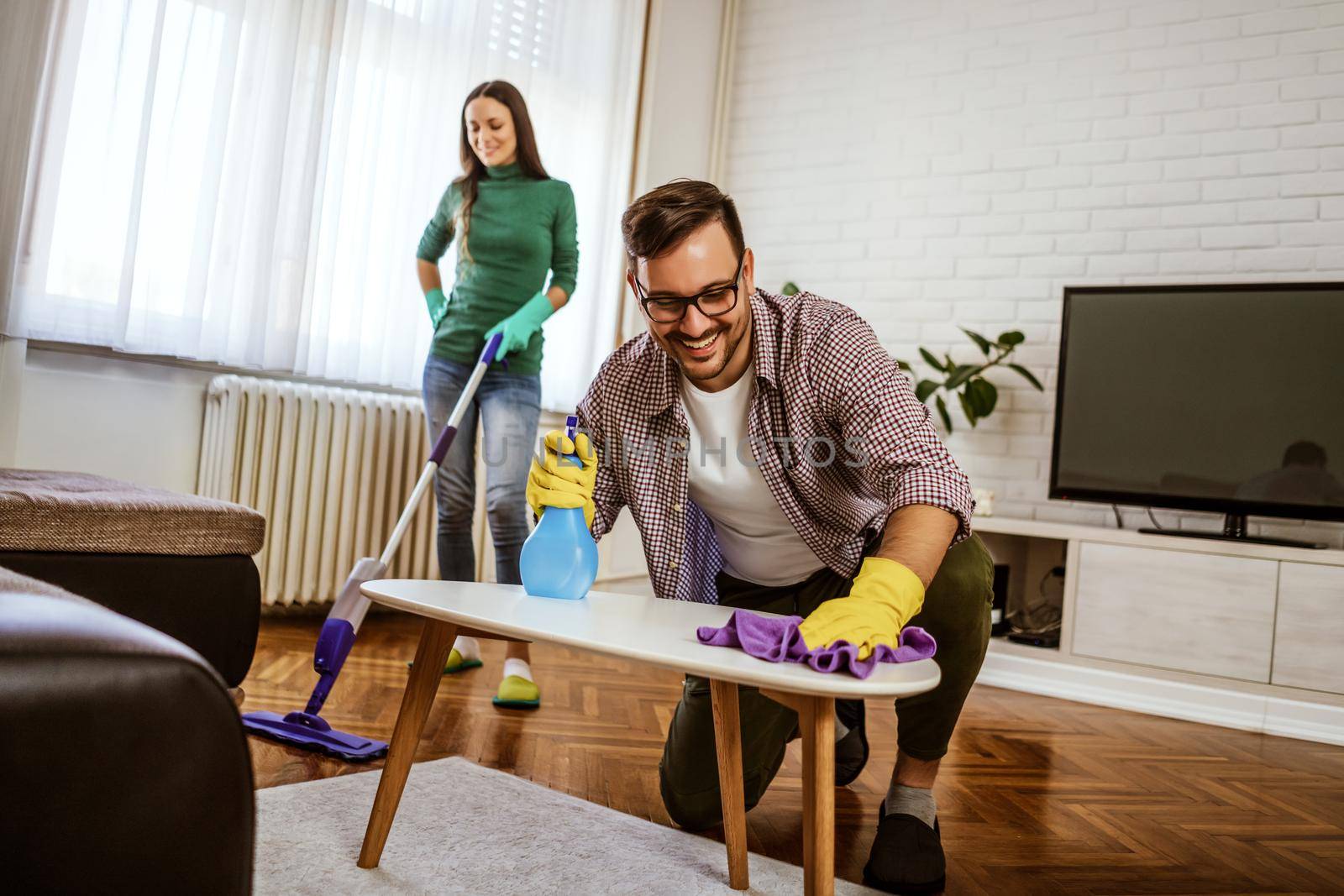 Young happy couple is cleaning their apartment.