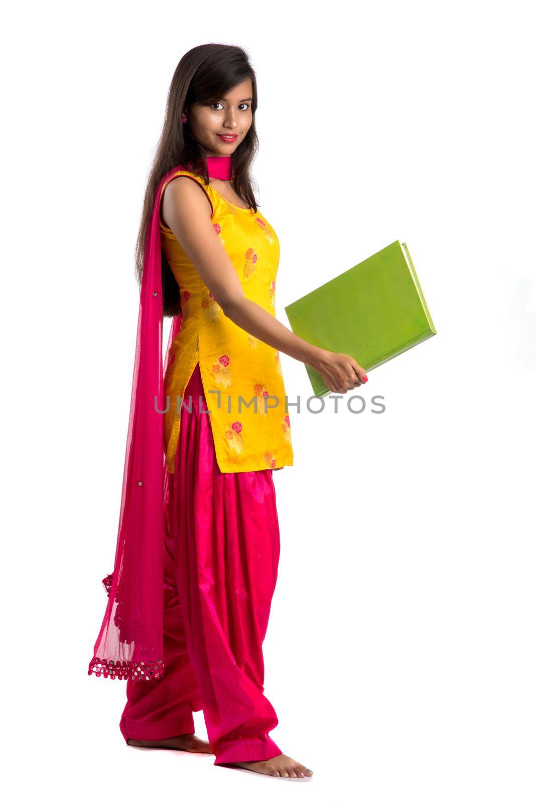 Pretty young girl holding book and posing on white background by DipakShelare