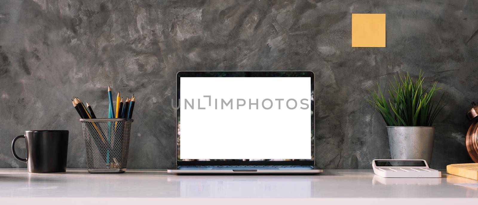 Cropped shot of workspace with mock-up laptop with white blank screen, Home interior or office background. by nateemee