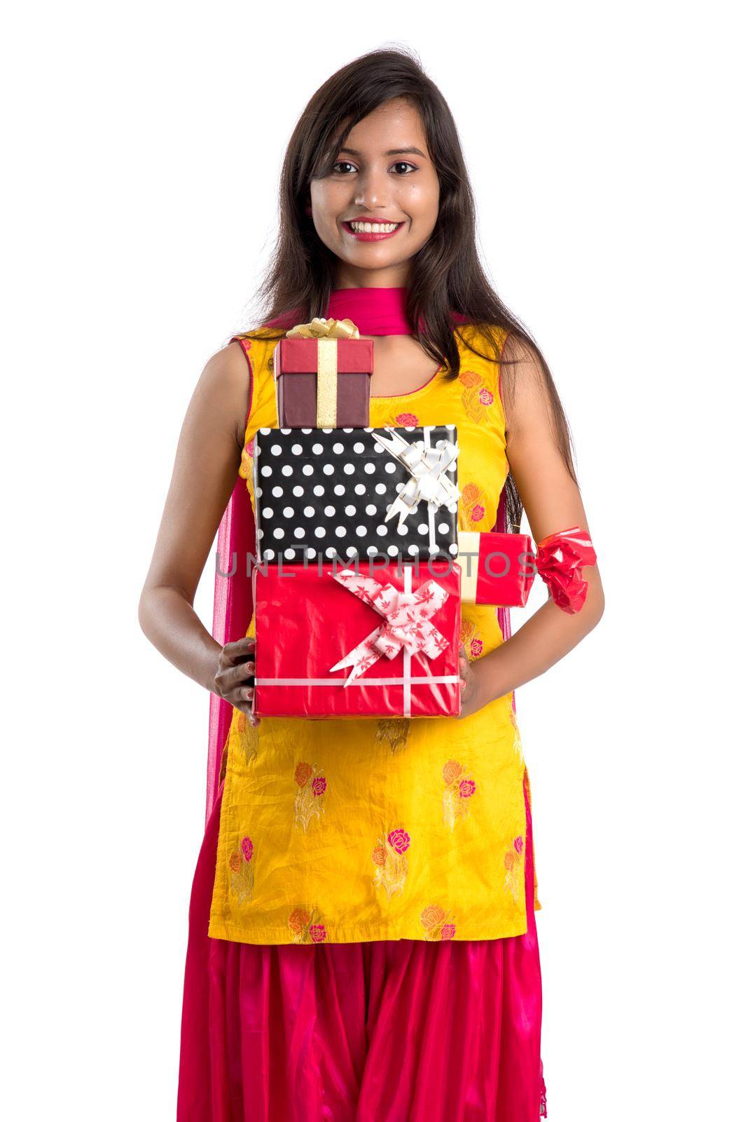 Portrait of young happy smiling Indian Girl holding gift boxes on a white background.