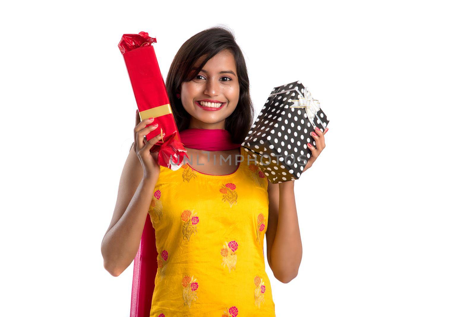 Portrait of young happy smiling Indian Girl holding gift boxes on a white background.