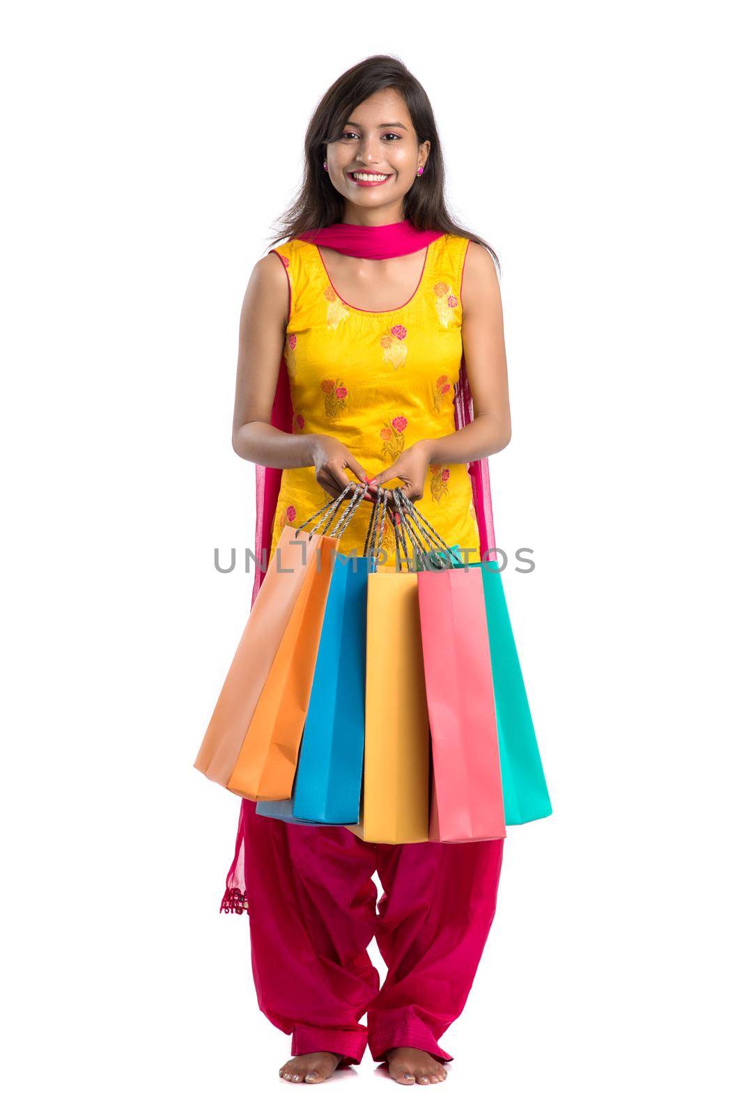 Beautiful Indian young girl holding and posing with shopping bags on a white background