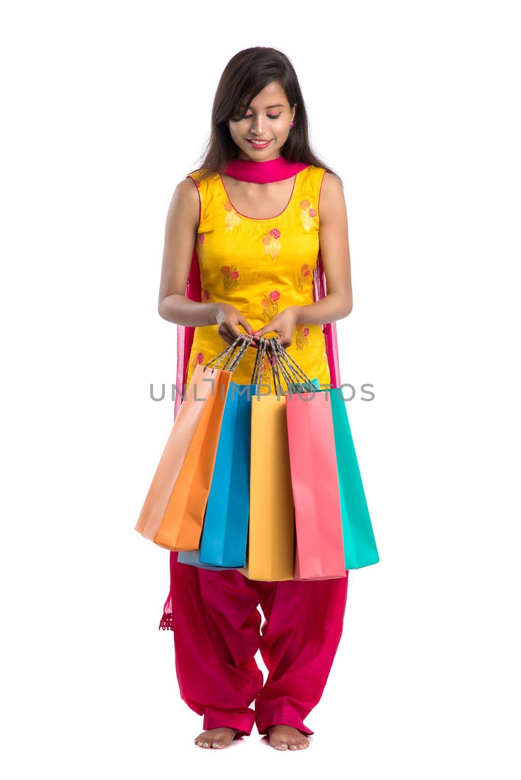 Beautiful Indian young girl holding and posing with shopping bags on a white background