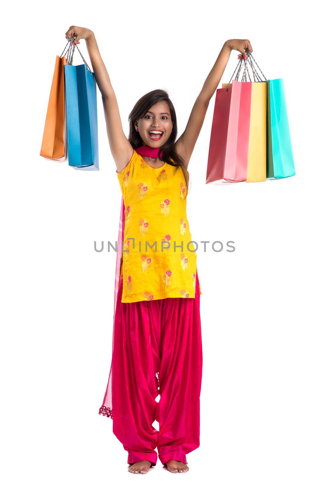 Beautiful Indian young girl holding and posing with shopping bags on a white background