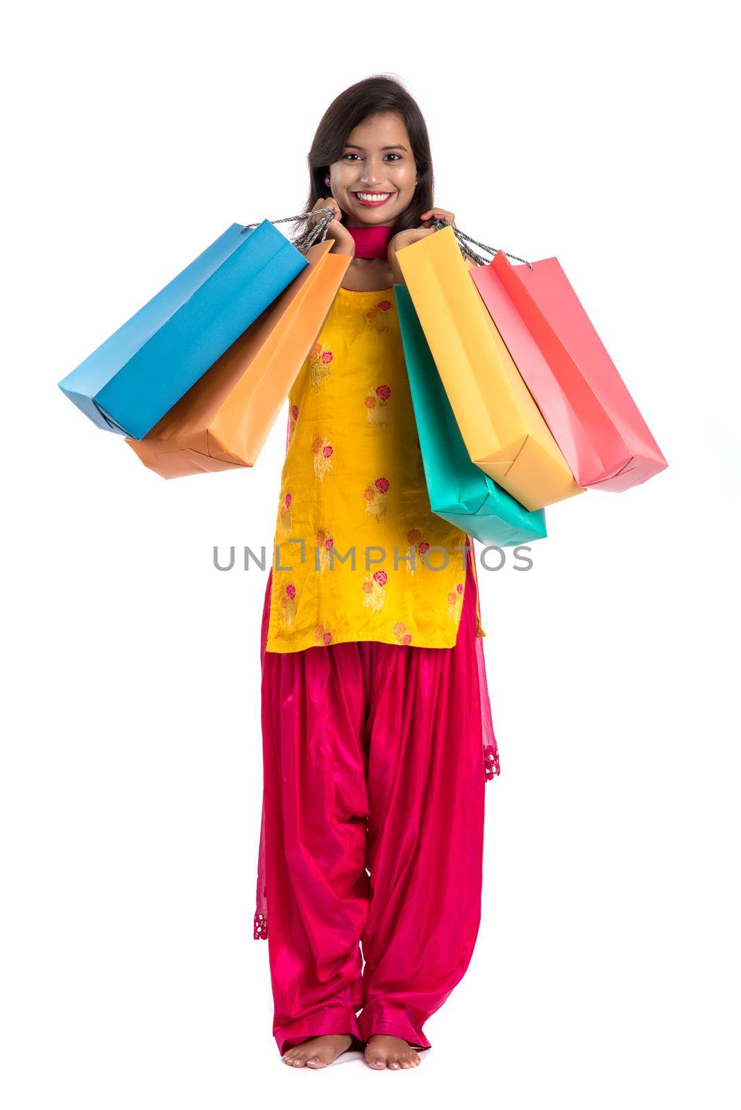 Beautiful Indian young girl holding and posing with shopping bags on a white background