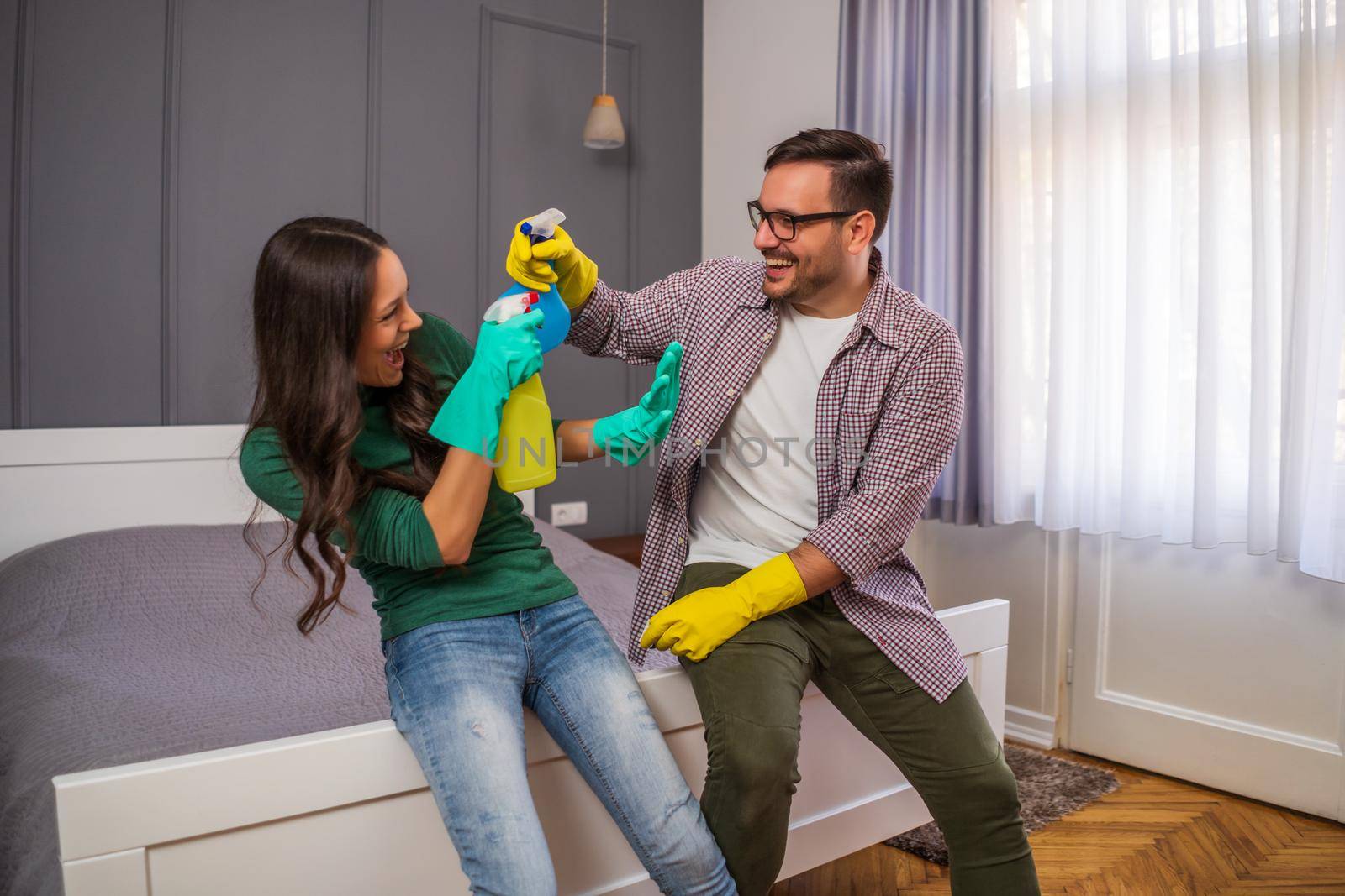 Young happy couple is having fun while cleaning their apartment.