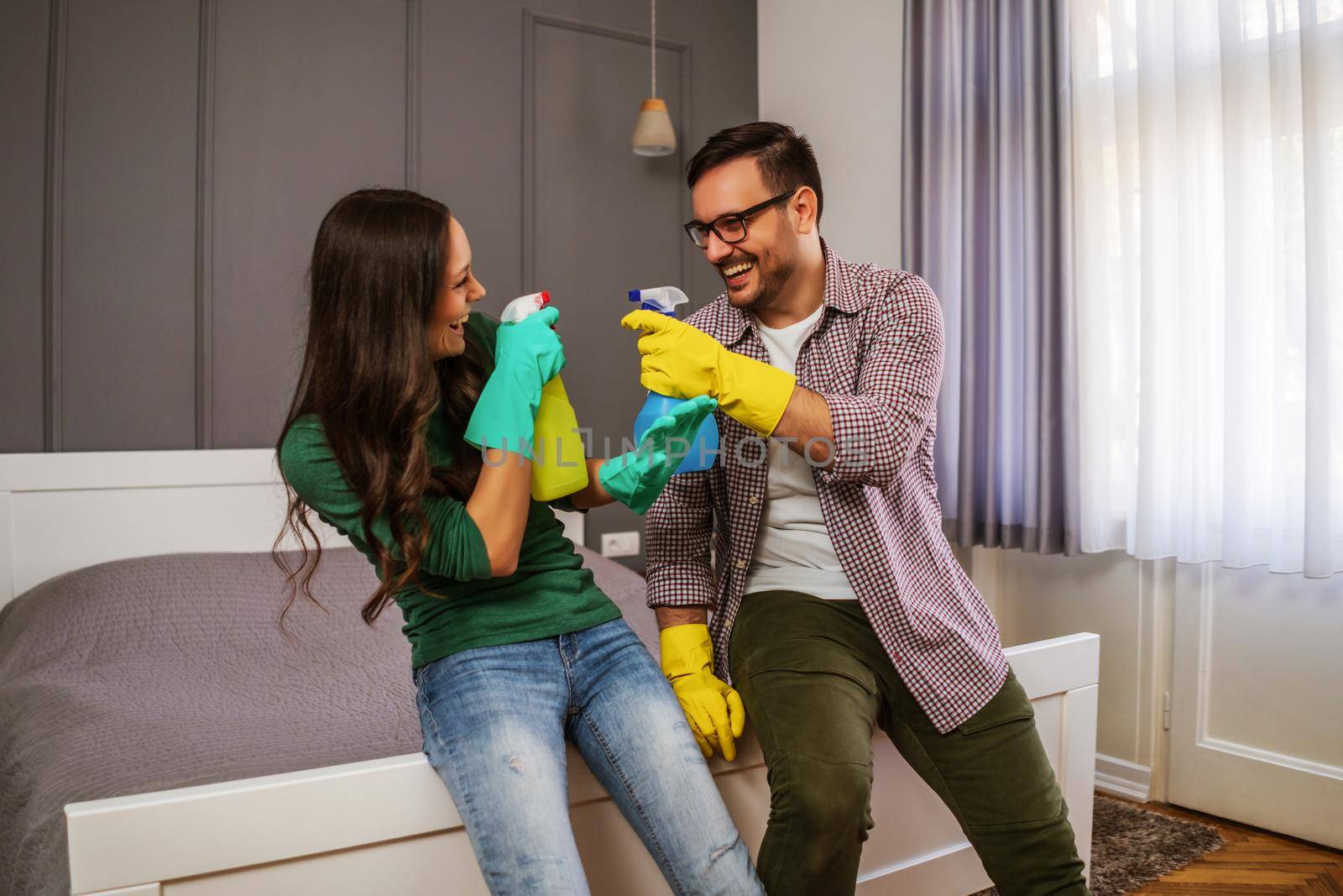 Young happy couple is having fun while cleaning their apartment.