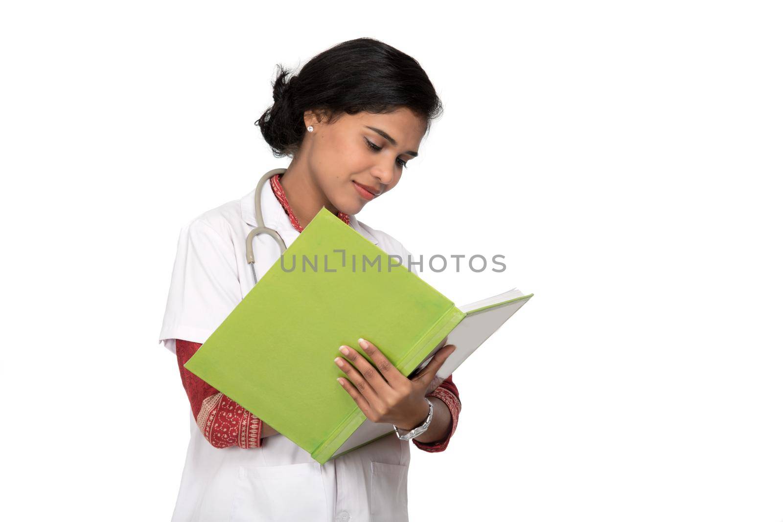 Young woman doctor with stethoscope is writing in book