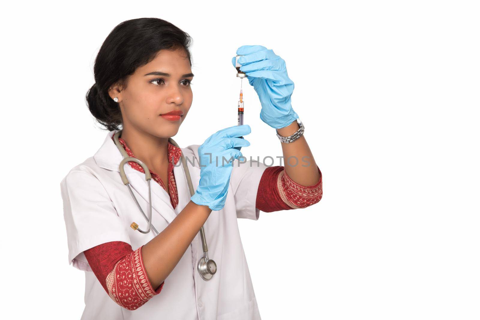 A female doctor with a stethoscope is holding an Injection or Syringe.