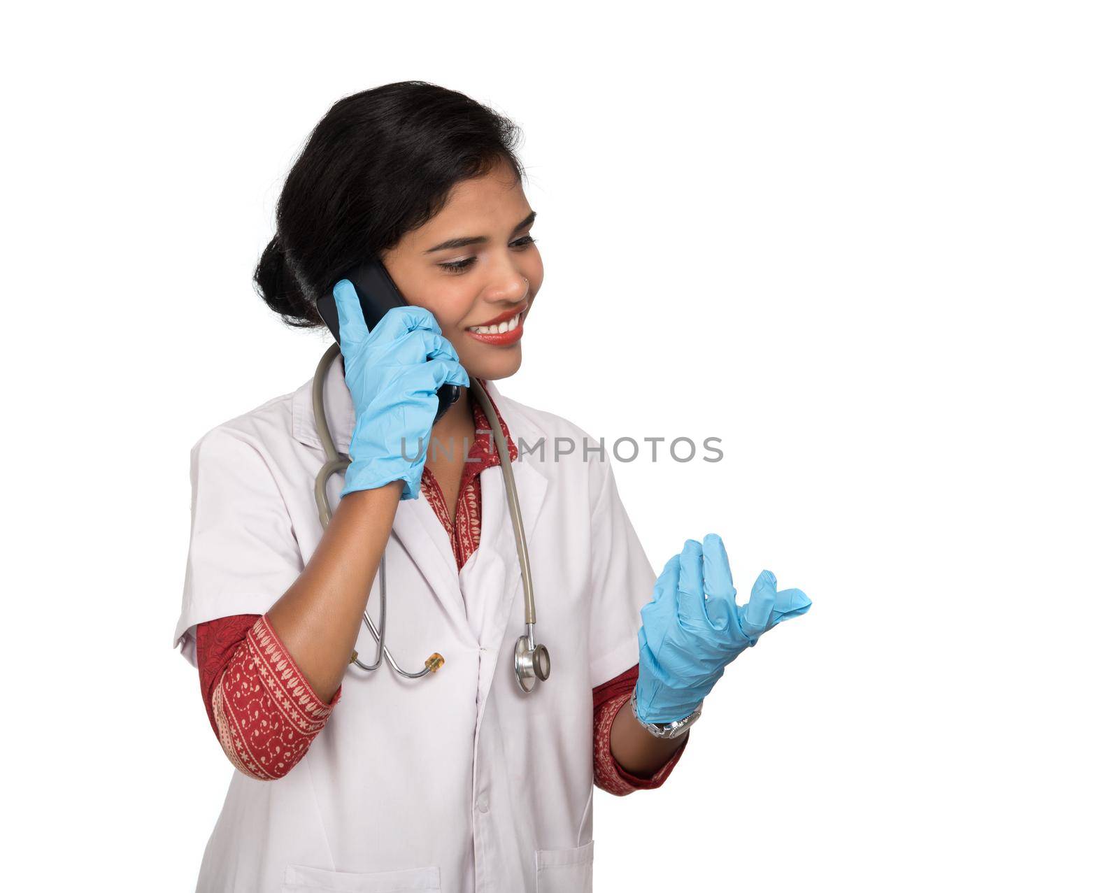 Female doctor with stethoscope talking on mobile phone on white background