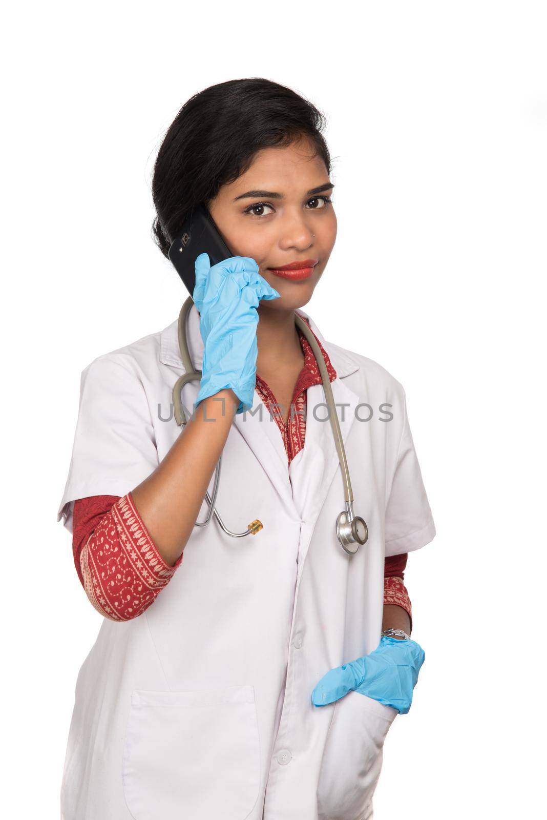 Female doctor with stethoscope talking on mobile phone on white background by DipakShelare
