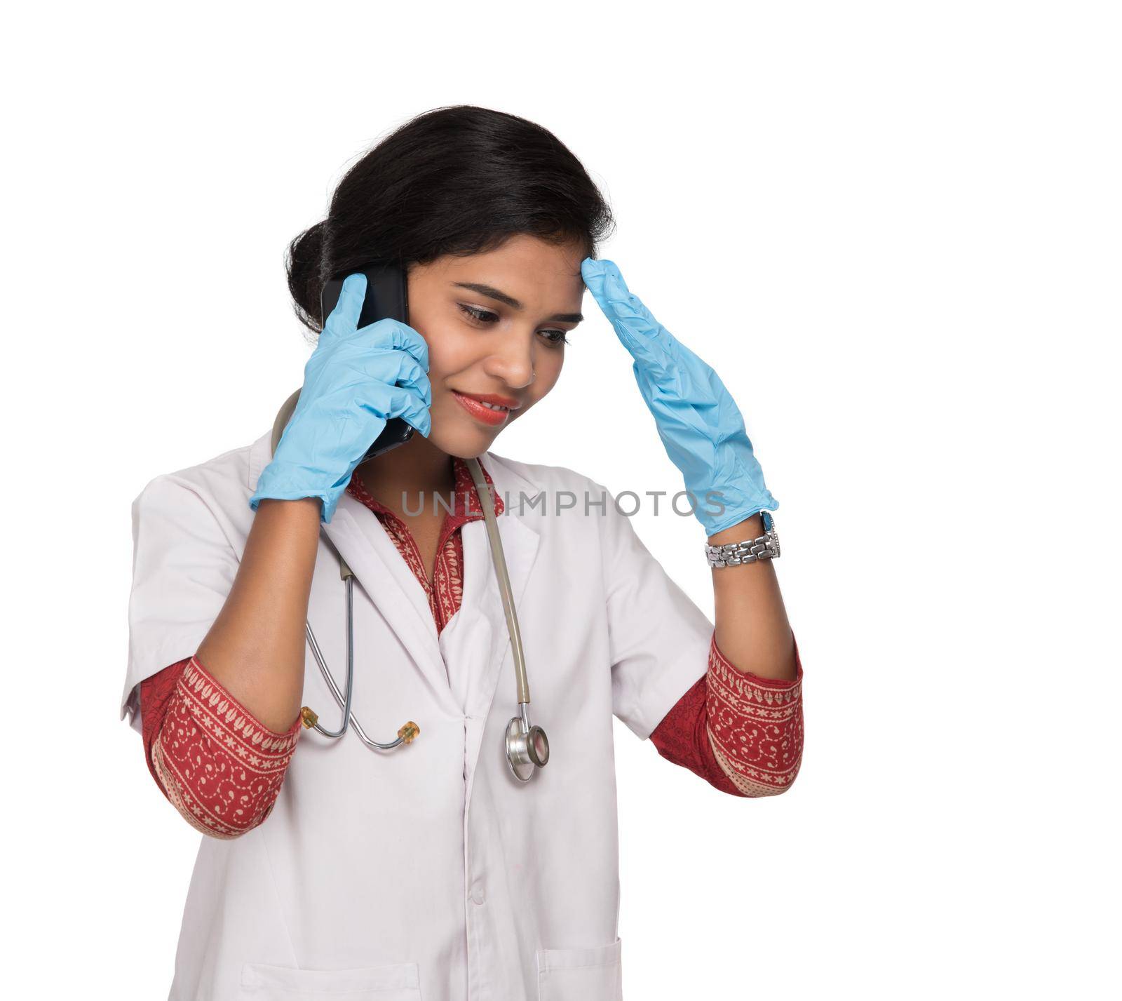 Female doctor with stethoscope talking on mobile phone on white background