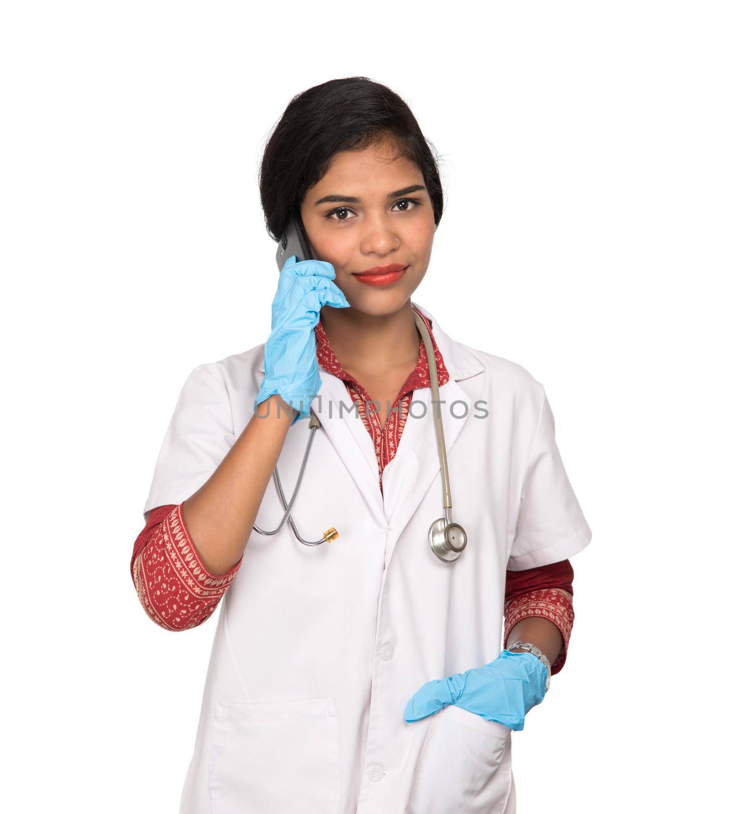 Female doctor with stethoscope talking on mobile phone on white background by DipakShelare