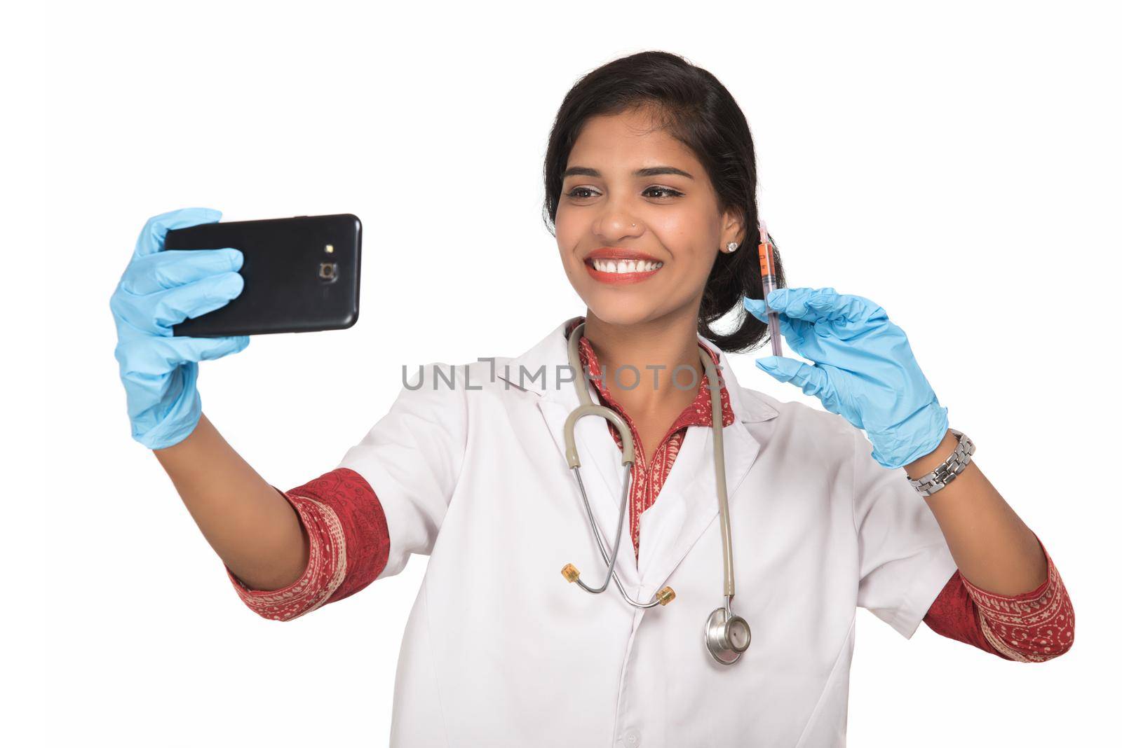 Female doctor taking selfie with stethoscope and injection by smartphone on white background. by DipakShelare