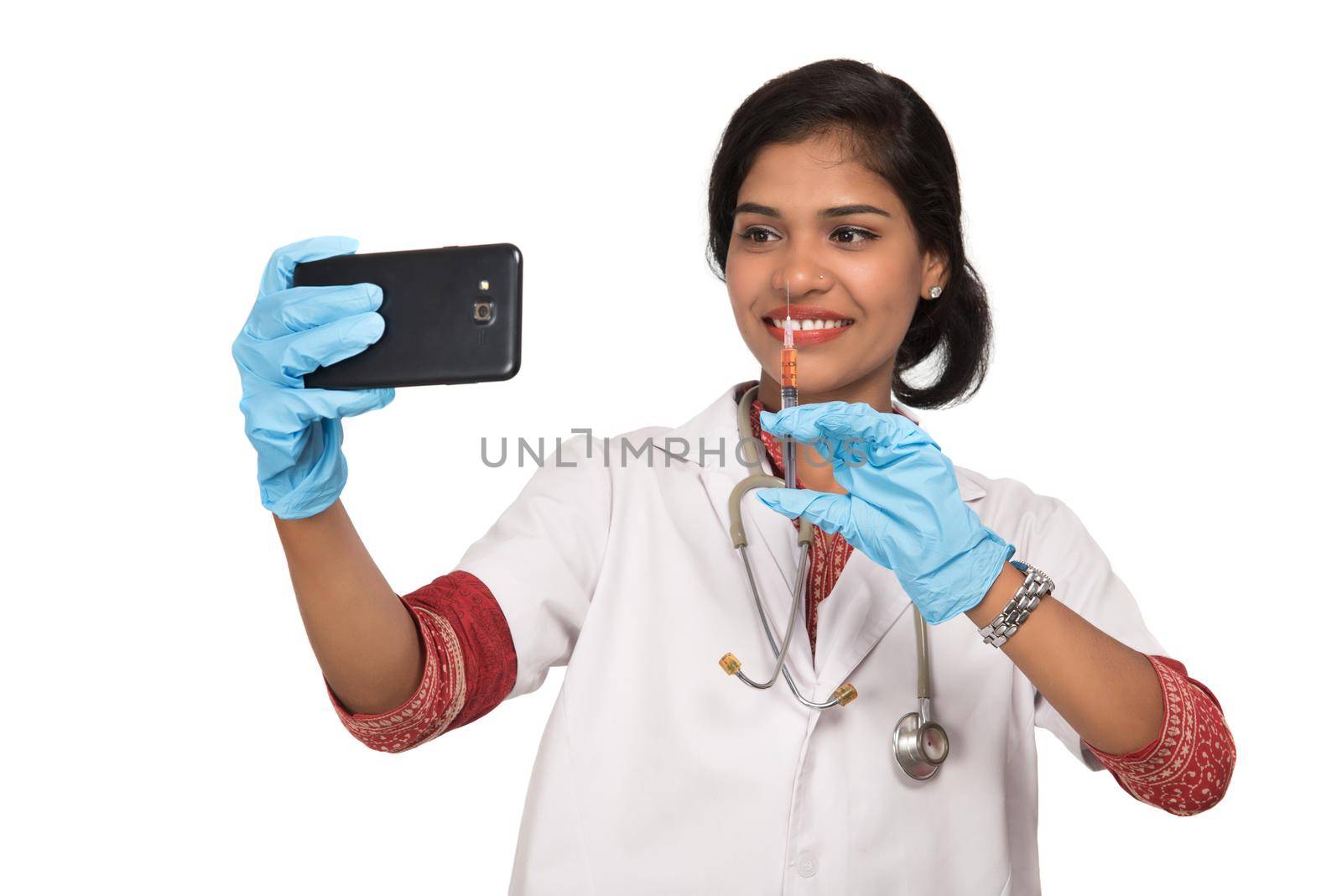 Female doctor taking selfie with stethoscope and injection by smartphone on white background. by DipakShelare
