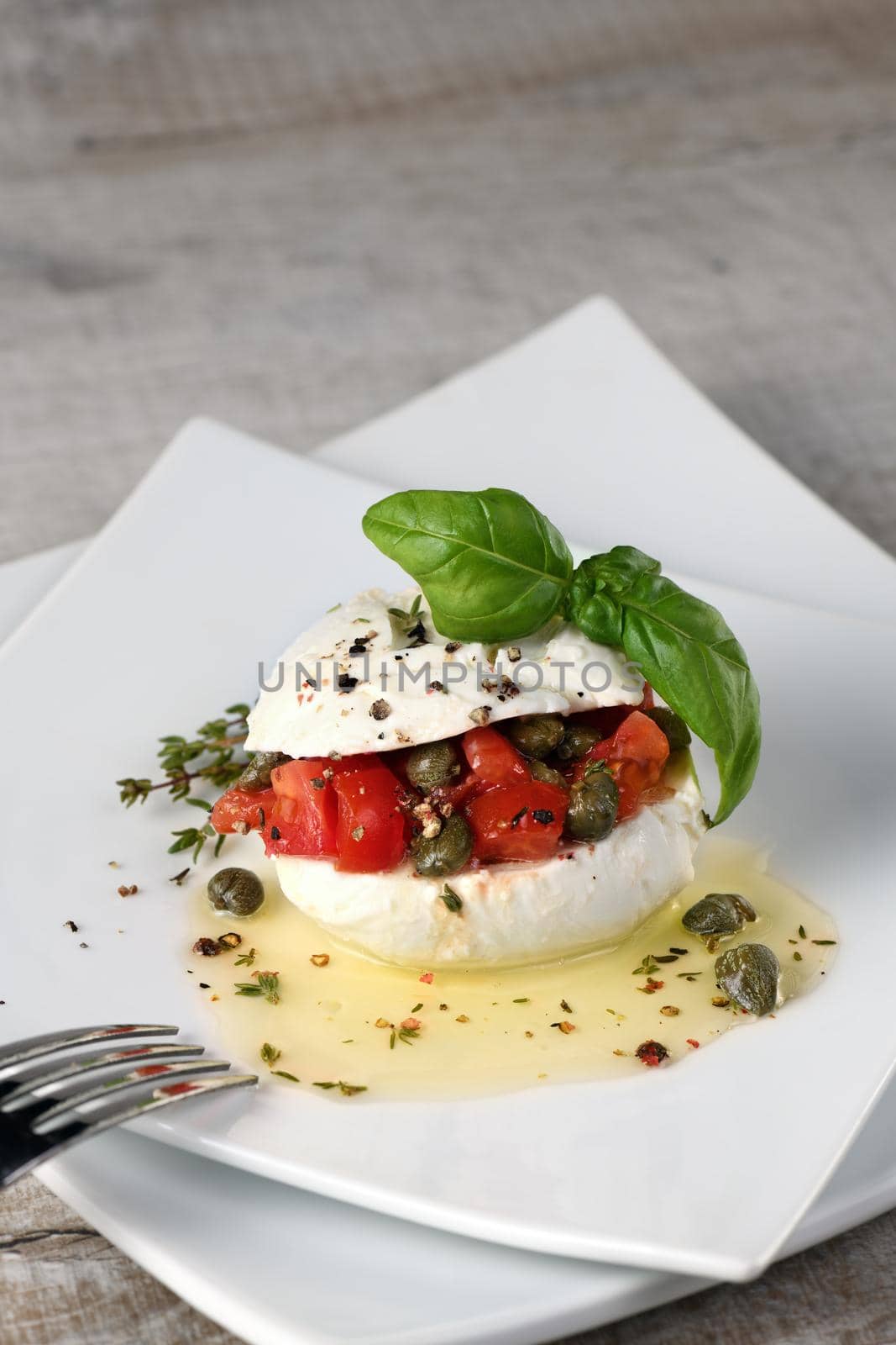 Mozzarella stuffed tomatoes with capers, seasoned   spices and basil in oil