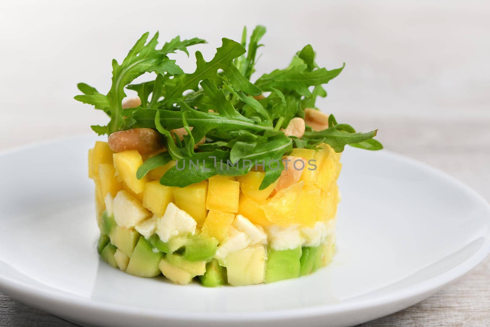 Fresh avocado, mango, mozzarella and arugula salad seasoned with nuts