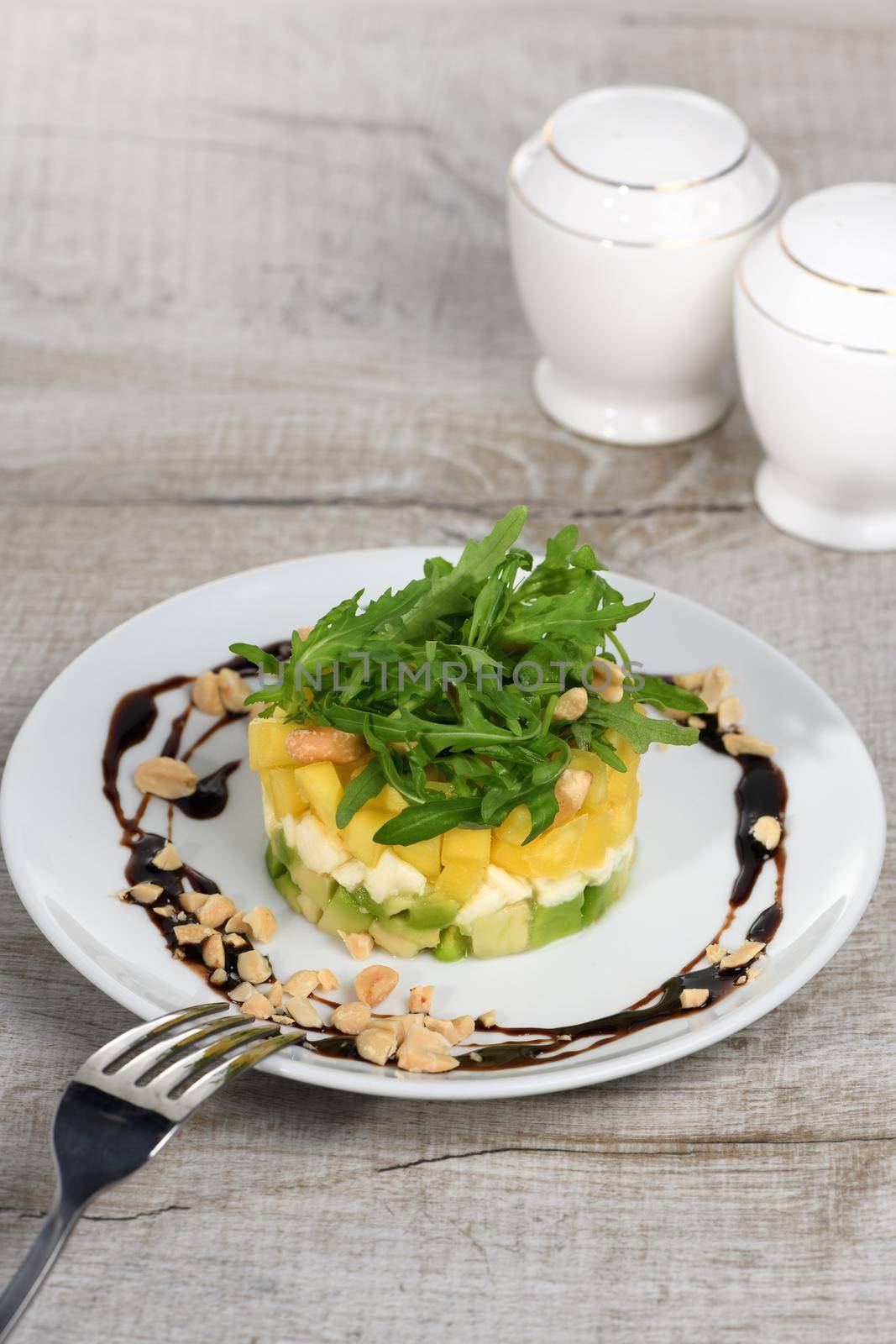 Fresh avocado, mango, mozzarella and arugula salad seasoned with nuts