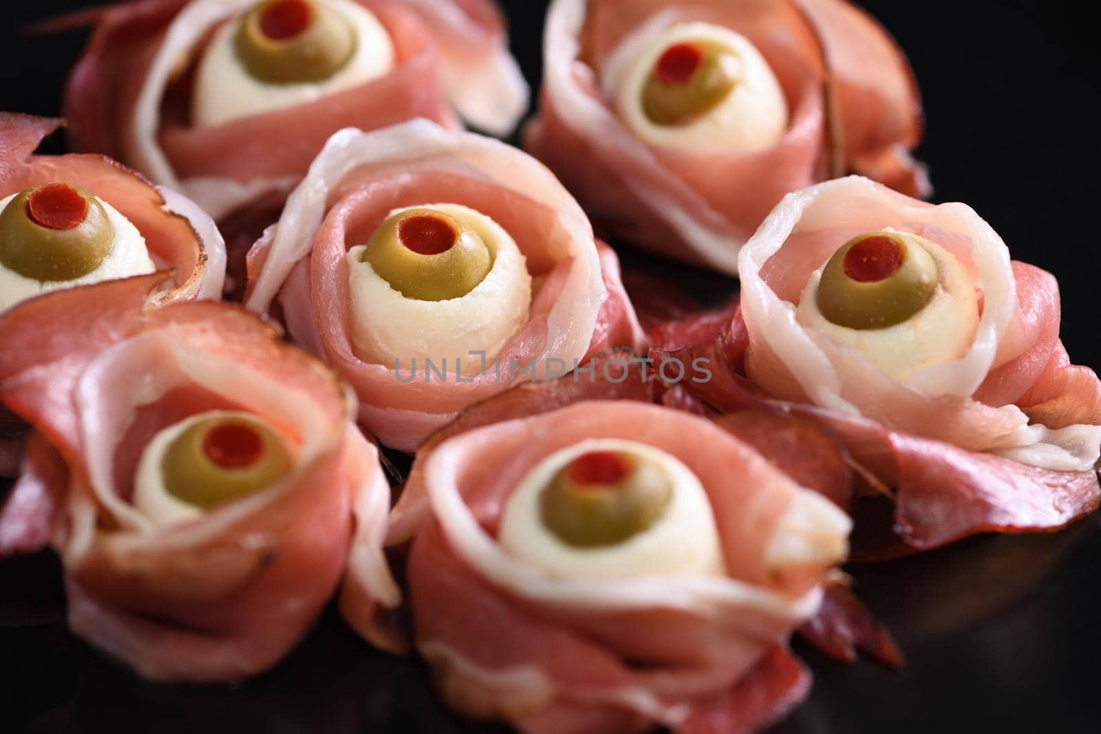Original Halloween snacks. Eyeballs cooked from  jamon with mozzarella, olives stuffed with red pepper