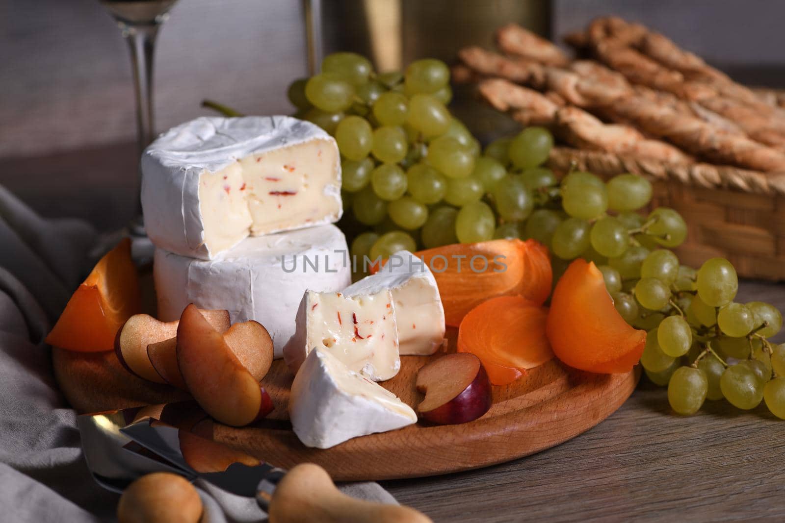 Cheese camembert with white grapes, sliced ​​persimmons and plums, a great appetizer for wine.