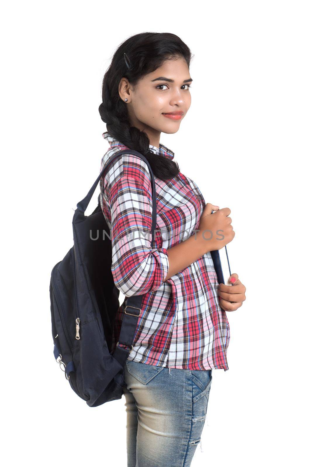 young Indian woman with backpack standing and holding notebooks, posing on a white background. by DipakShelare