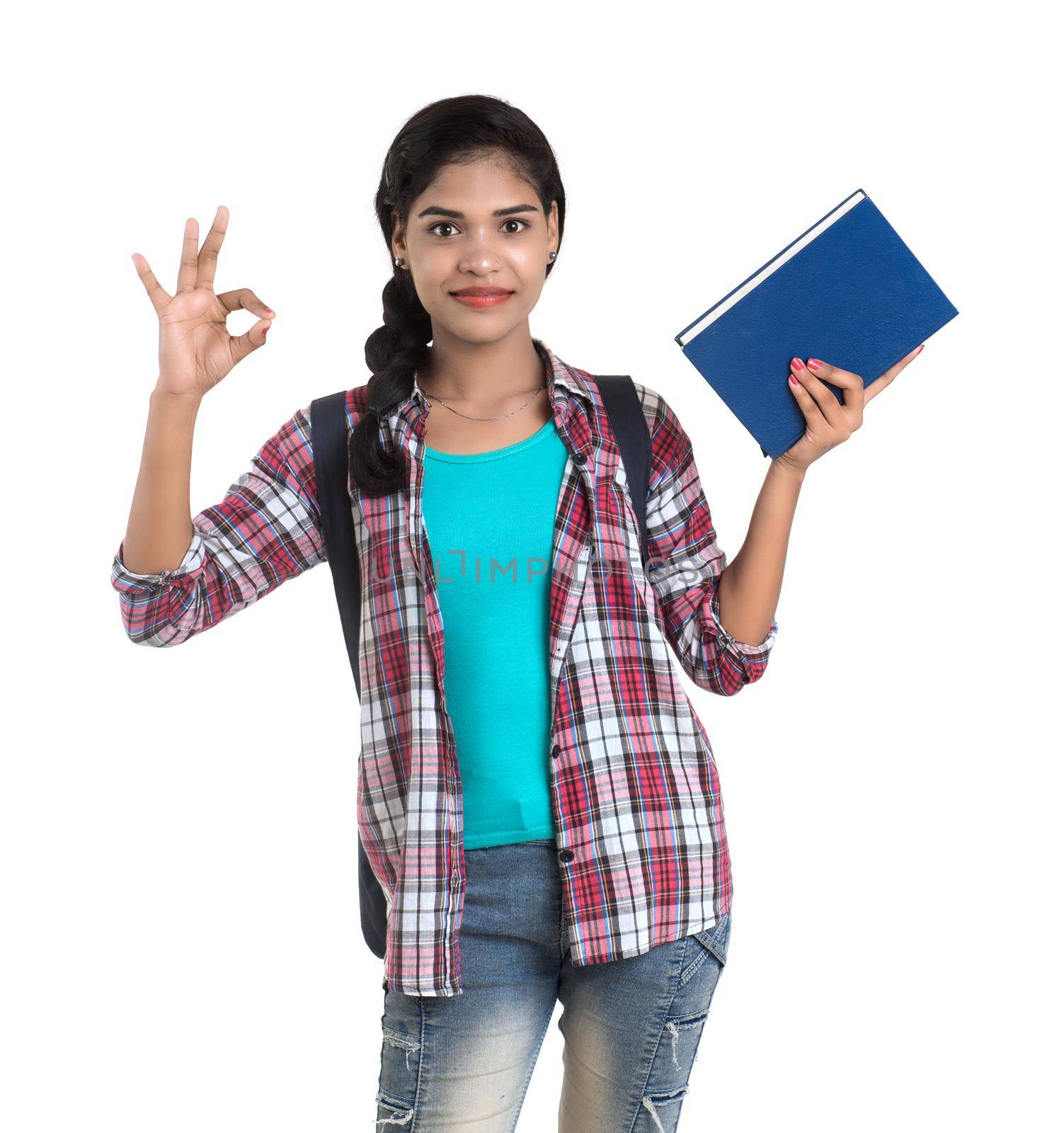 young Indian woman with backpack standing and holding notebooks, posing on a white background.