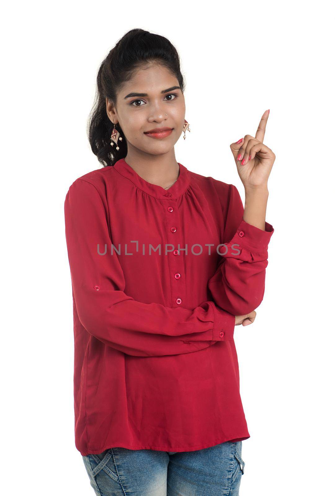 Young smiling girl pointing fingers to copy space on a white background