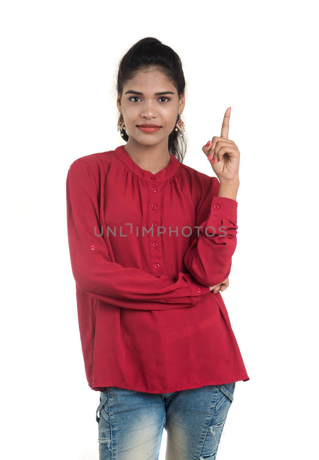 Young smiling girl pointing fingers to copy space on a white background