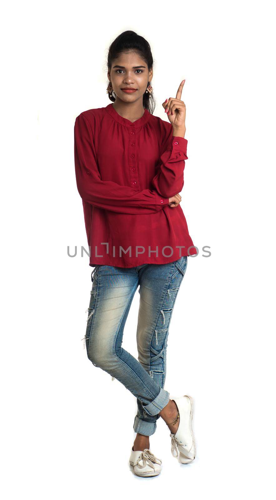 Young smiling girl pointing fingers to copy space on a white background