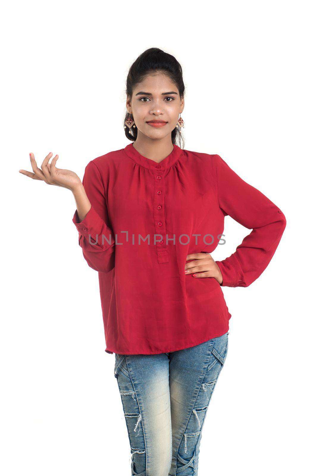 Young smiling girl pointing fingers to copy space on a white background by DipakShelare