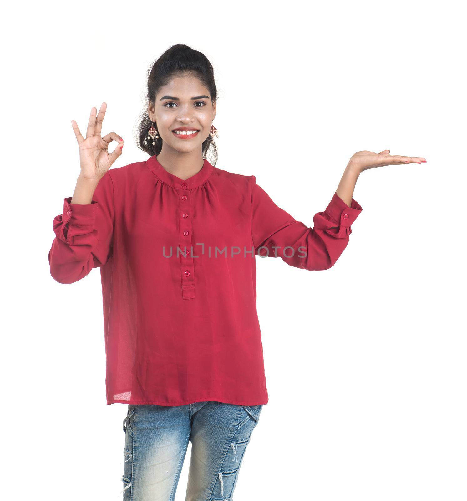 Young smiling girl pointing fingers to copy space on a white background by DipakShelare