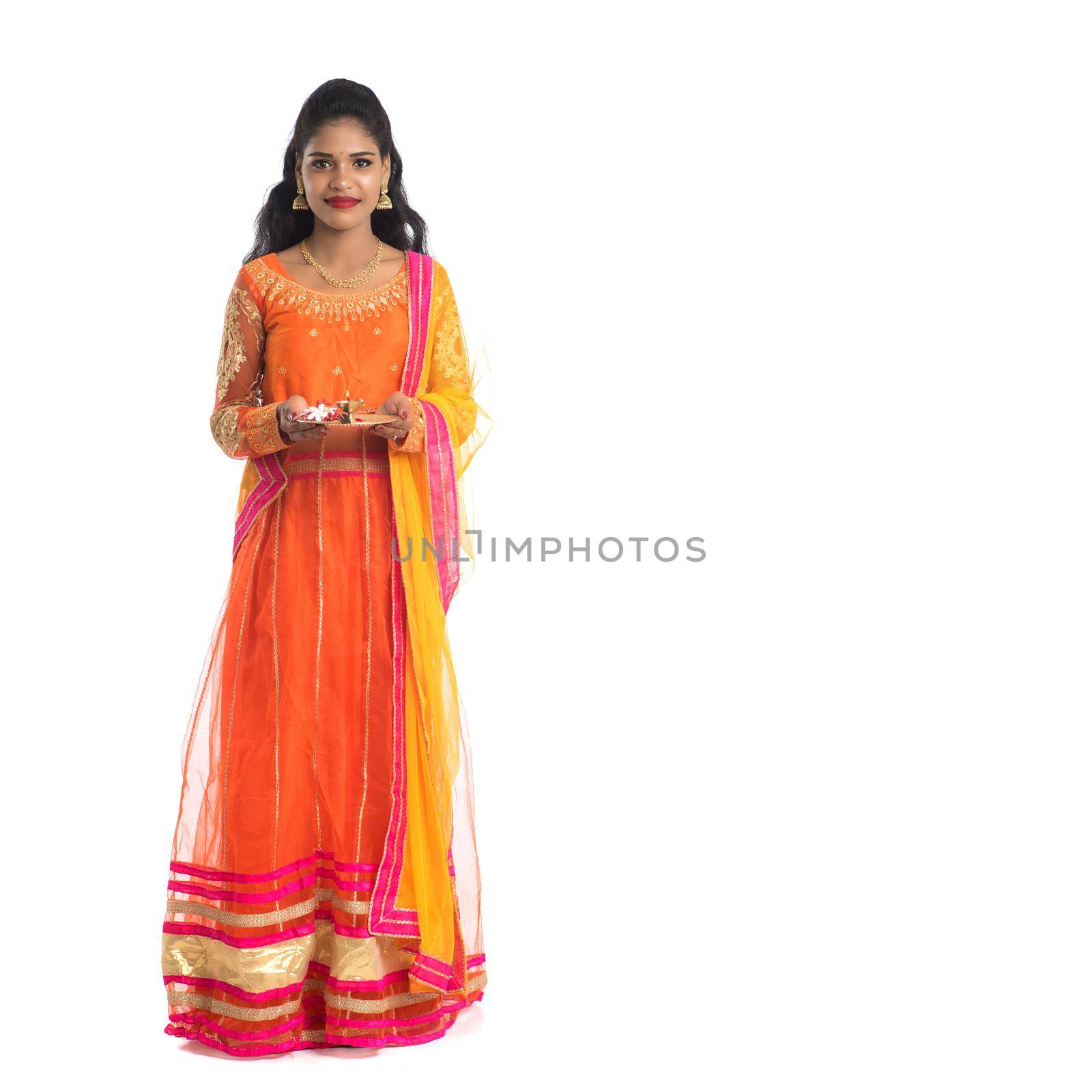 Beautiful Indian young girl holding pooja thali or performing worship on a white background