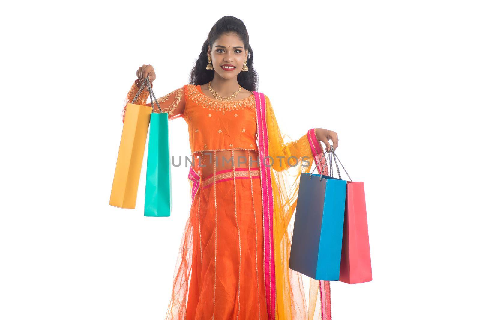 Beautiful Indian young girl holding shopping bags while wearing traditional ethnic wear. Isolated on a white background