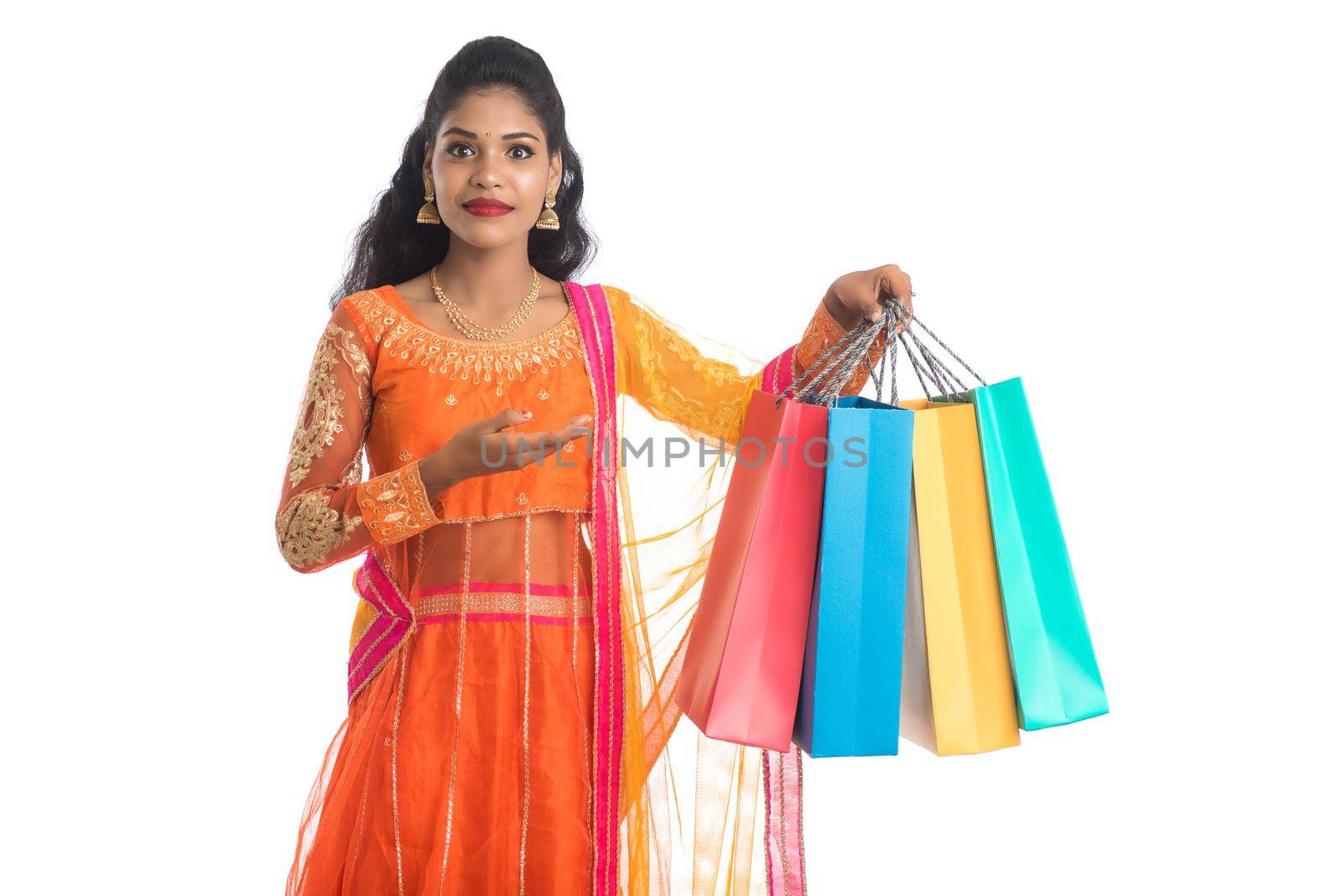 Beautiful Indian young girl holding shopping bags while wearing traditional ethnic wear. Isolated on a white background