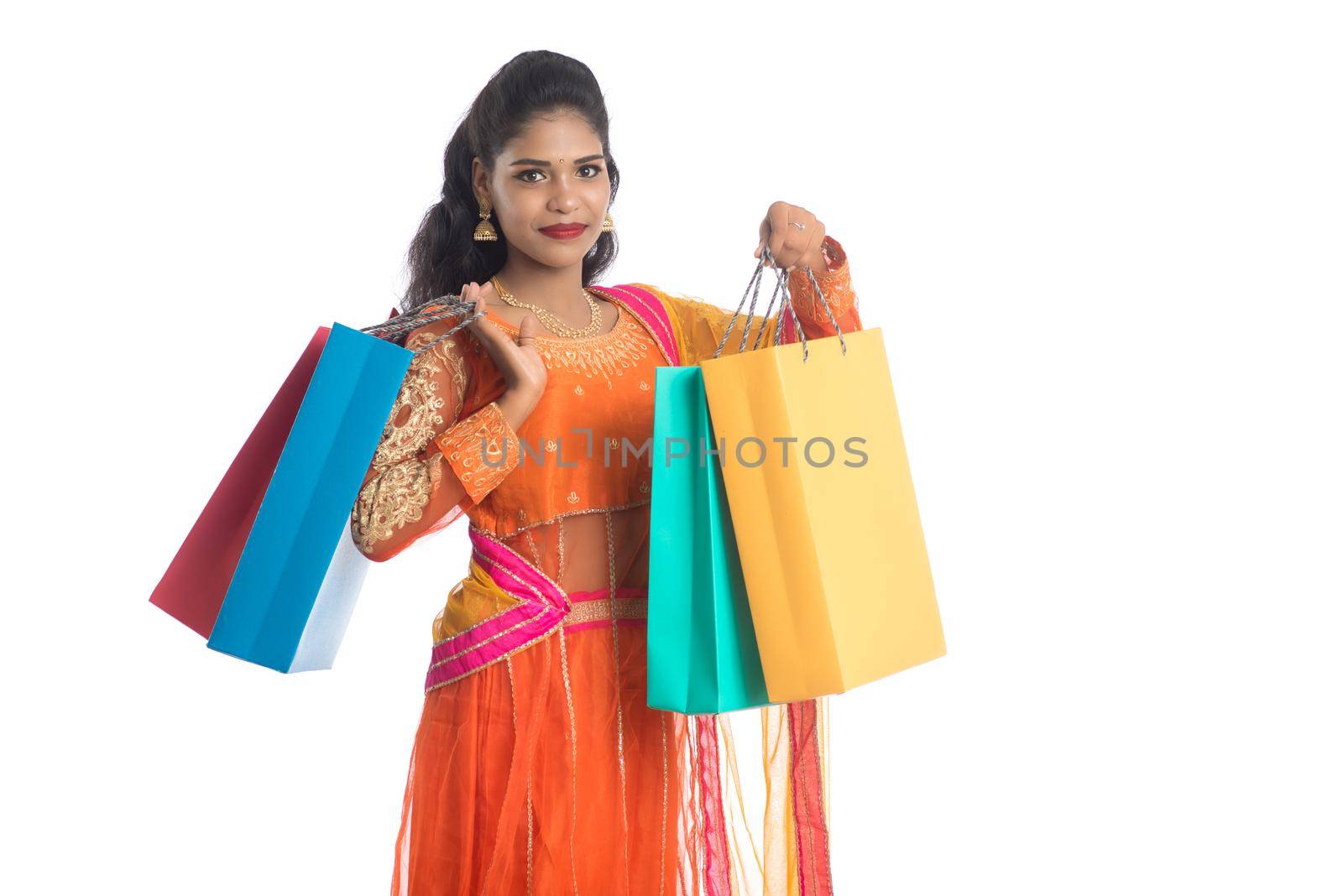 Beautiful Indian young girl holding shopping bags while wearing traditional ethnic wear. Isolated on a white background