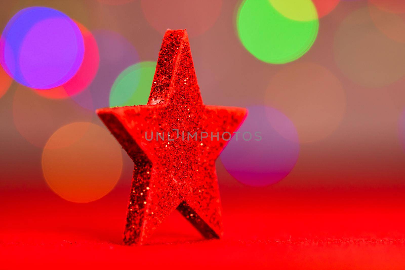 Red glittery decoration in a colorful Christmas composition isolated on background of blurred lights. by vladispas
