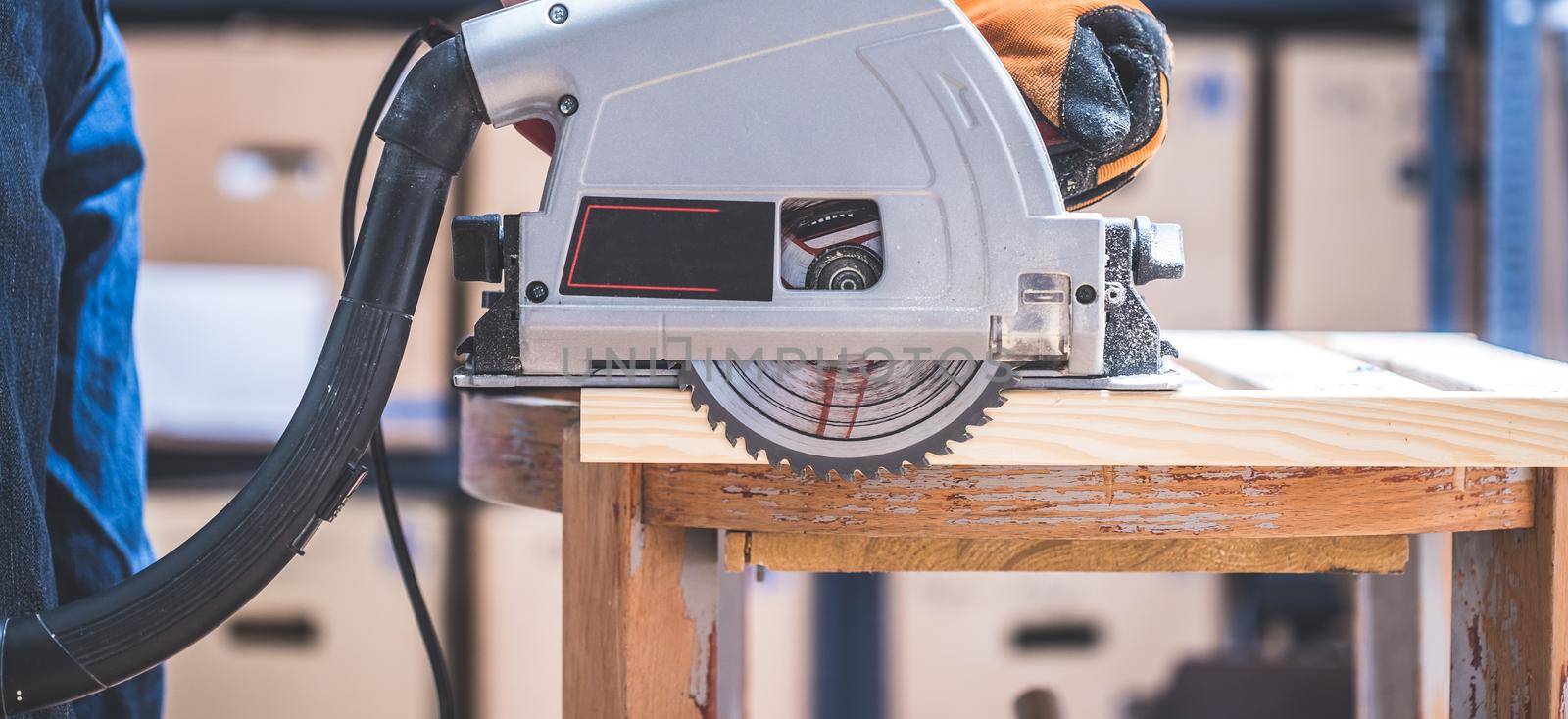 Sawing wood in the garage: Home handyman sawing plank of wood with circular saw by Daxenbichler