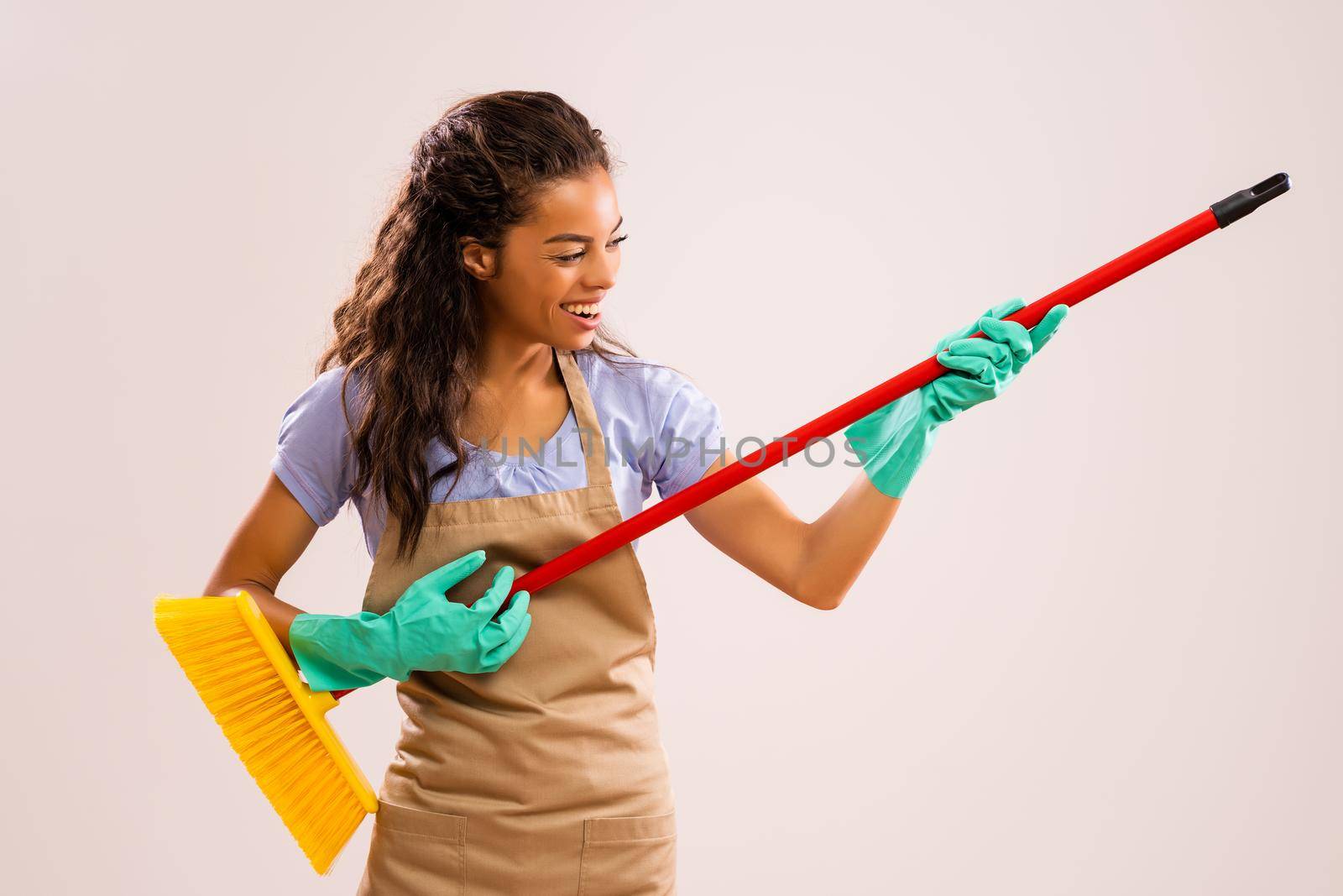 Portrait of happy and successful african-american professional maid having fun with broom.