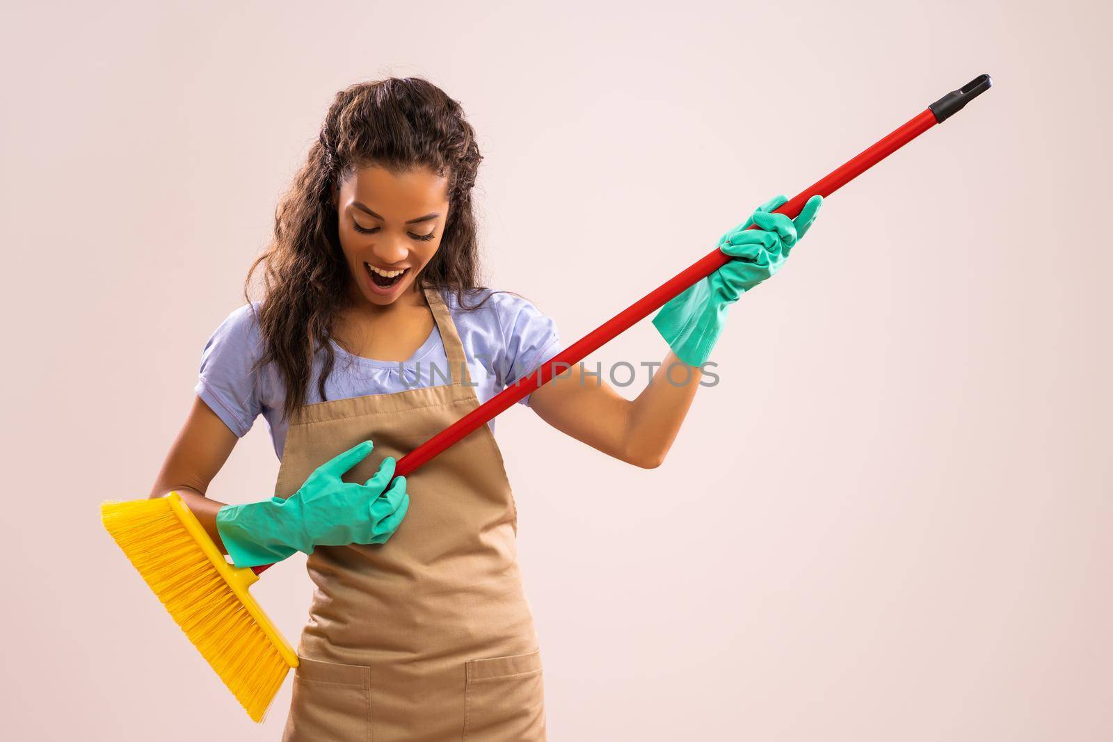 Portrait of happy and successful african-american professional maid having fun with broom.
