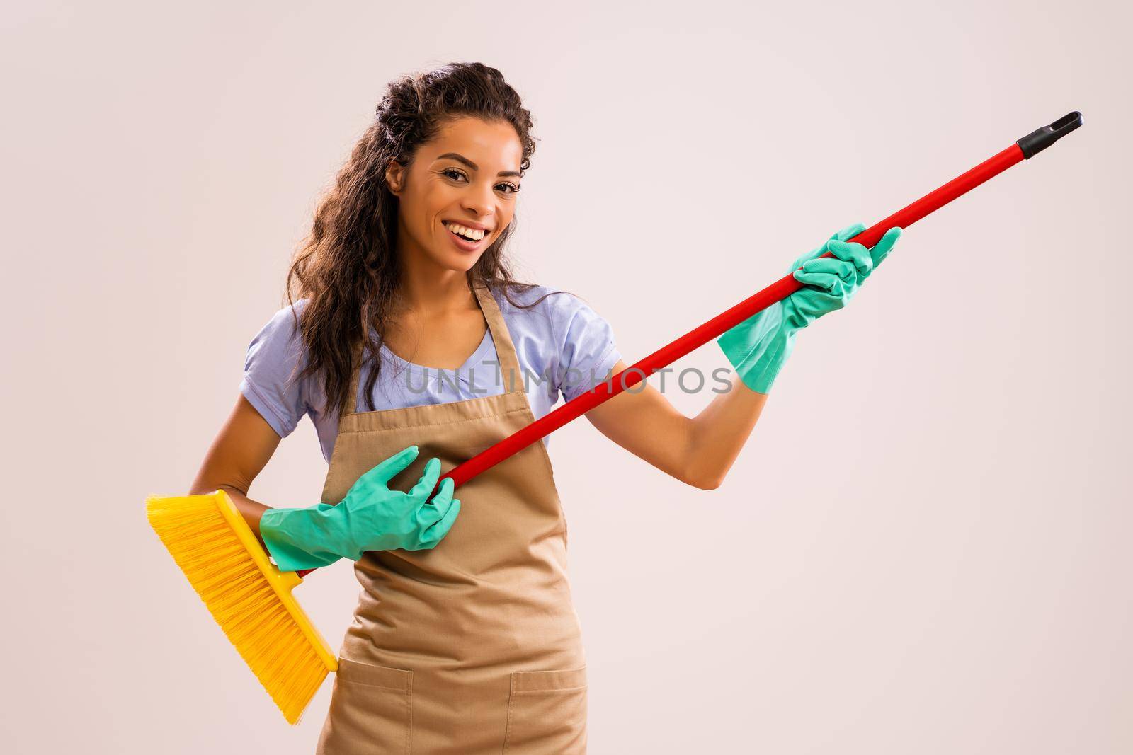 Portrait of happy and successful african-american professional maid having fun with broom.